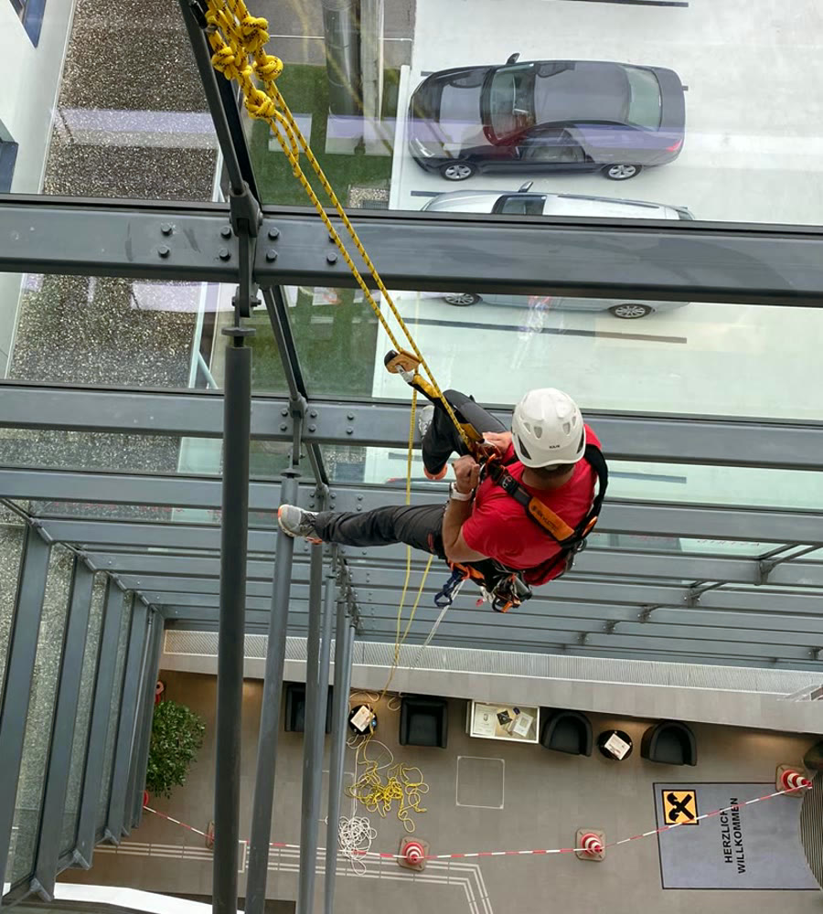 Höhenarbeiter im Seilzugang an einer Glasfassade.